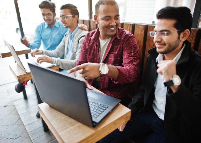 Group of four indian teen male students. Classmates spend time t Group of four indian teen male students. Classmates spend time together and work at laptops.